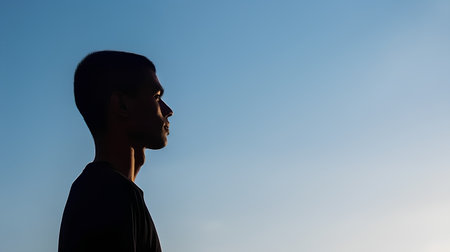 Silhouette of a young man on the background of blue skyの素材