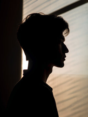 Silhouette of a man in front of a window with blindsの素材
