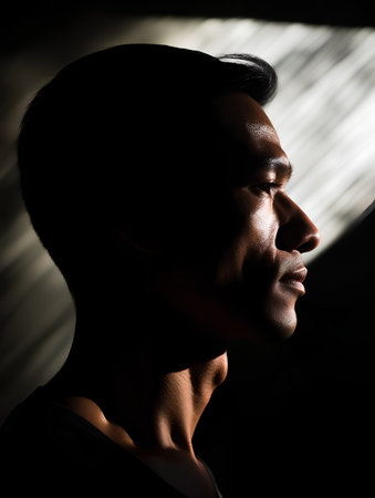 Portrait of a handsome young man in profile against a dark backgroundの素材