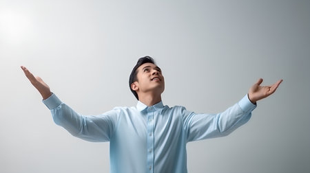Young asian business man in blue shirt with hands up on grey backgroundの素材