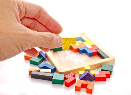 a hand holding a piece of wooden jigsaw 