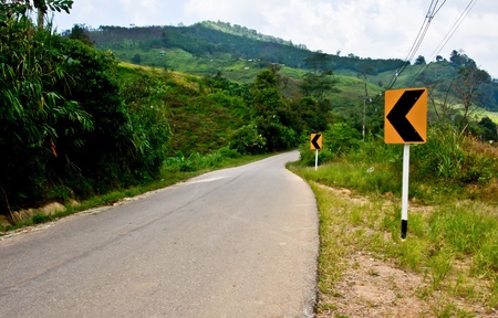 local road in Thailand with curve warning signの写真素材