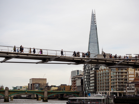 people cross Millennium bridge in London, UKの写真素材