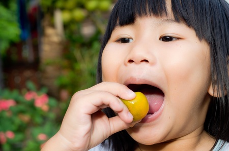 Asian girl eating sour orangeの写真素材