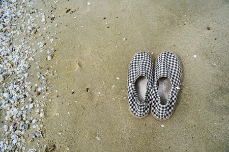 Retro black and white plaid shoes canvas on wet sand.の写真素材