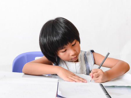 Asian girl doing homework at home, isolated on white.の写真素材