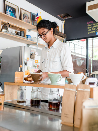 Barista brews a single cup a coffee house employee brew a single cup of coffee using a unique system. The hot water drips through the filterの写真素材
