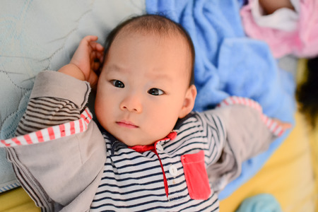 Close up Asian baby lying on bed.の写真素材