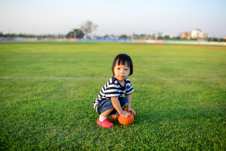 Asian girl playing ball in green field.の写真素材