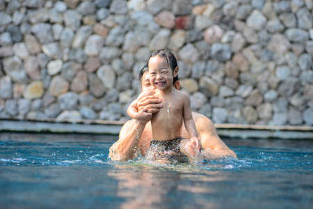 Happy Asian father and his child have fun at pool.の写真素材