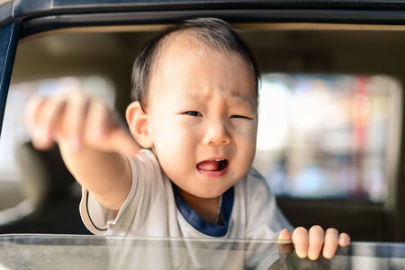 Crying Asian baby in car, safety concept.