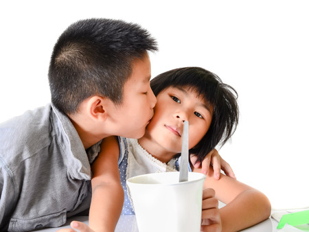 Asian brother kissing his sister with love at home.の写真素材