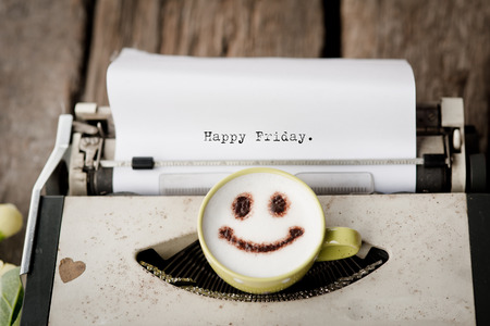 Happy Friday on typewriter with happy face coffee cup, sepia tone.の写真素材