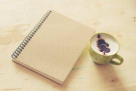 Cup of coffee with white board on wooden table.
