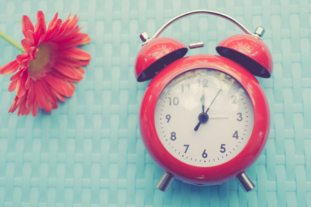 Retro alarm clock and gerbera flower on blue texture background.の写真素材