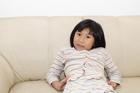 Portrait of Asian little girl sitting on sofa at home.の写真素材