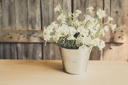 Vintage style White flowers stainless pot on wooden background, still life.の写真素材