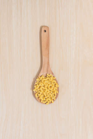 Macaroni on paddle with wooden background.の写真素材