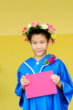 happy children graduation gown isolated on yellow background.の写真素材