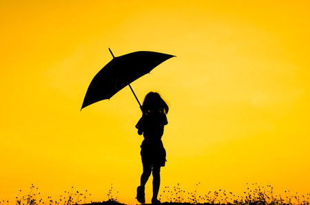 Umbrella girl with sunset silhouetteの写真素材