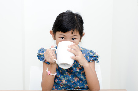 Asian girl holding a cup of milk during breakfast at home.の写真素材