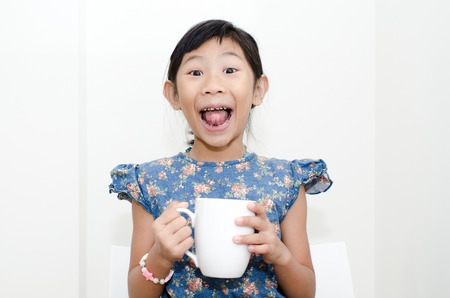 Asian girl holding a cup of milk during breakfast at home.の写真素材