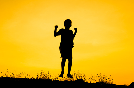 Boy raising his hands standing during sun setの写真素材