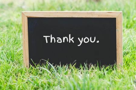 Thank you message on blackboard on green grass.の写真素材