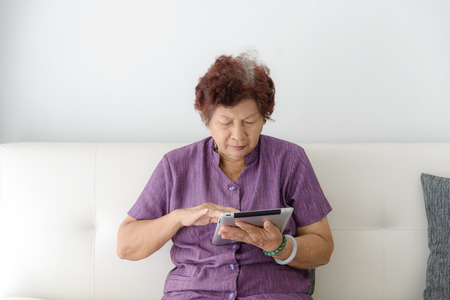 Asian senior woman at home connected on internetの写真素材