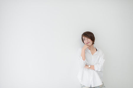 attractive asian woman standing on floor with white wall.の写真素材