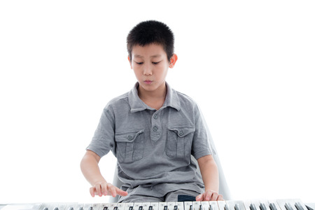 Asian boy playing keyboard on white.の写真素材