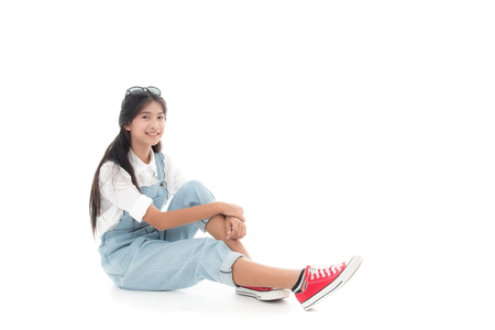 Asian teenage girl smiling sitting on chair with white background.の写真素材