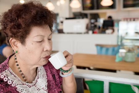 Asian senior woman enjoying cup of tea in coffee shop.の写真素材
