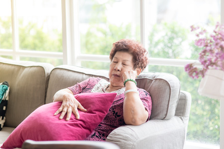 Asian senior Woman Resting on Couch with Pillow at the Living Room.の写真素材