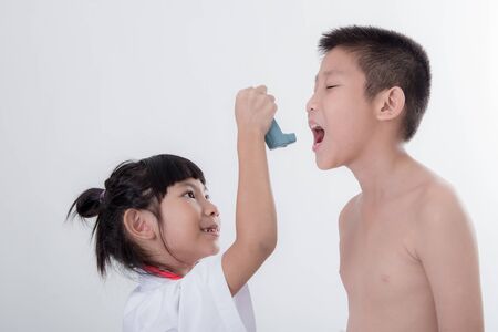 Small girl in doctor's coat inhaling medicine with patientの写真素材