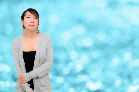 Chinese Asian woman Model wearing grey cardigan on blurry blue bokeh background.の写真素材