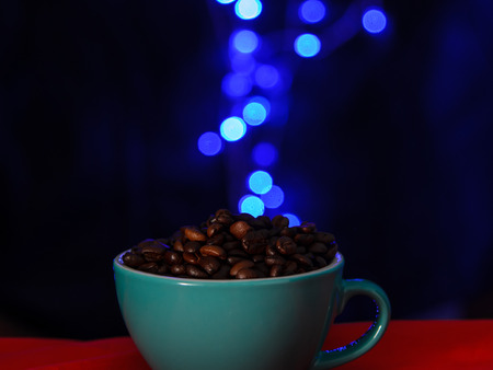 Coffee beans on mug with blue bokeh blurry background.の写真素材