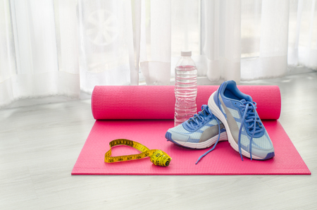 Sport shoes, yoga mat, bottle of water and centimeter on wooden background. Sport equipment. Concept healthy life. Selective focusの写真素材