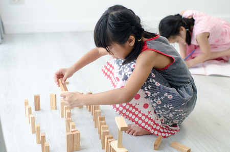 Asian children playing wooden blocks on floor at home.の写真素材