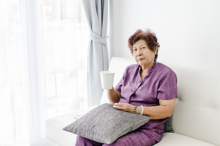 Old woman drinking a cup of coffee or tea at home.の写真素材
