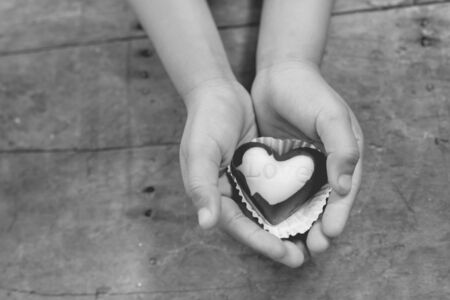 Black and white Love note on black and white chocolate in kid's handの写真素材
