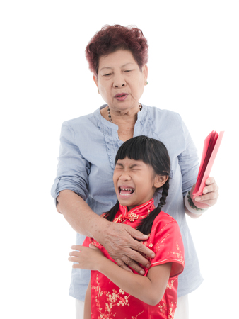Crying girl wearing red Chinese suit with red envelope with her grandmother.の写真素材