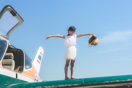Asian girl walking on plane wing with blue sky.の写真素材