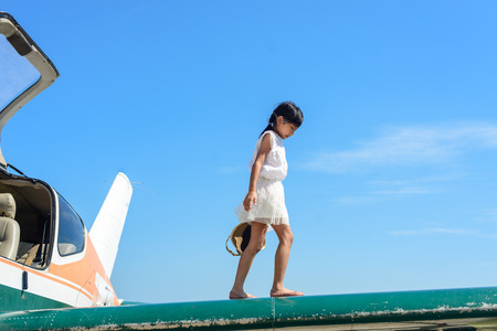 Asian girl walking on plane wing with blue sky.の写真素材