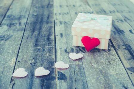 Gift box and red heart shape on wooden table.  Vintage filter effect.