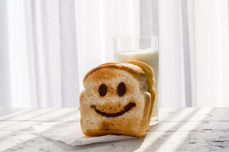 Happy toasted on wooden table with warm window light.の写真素材