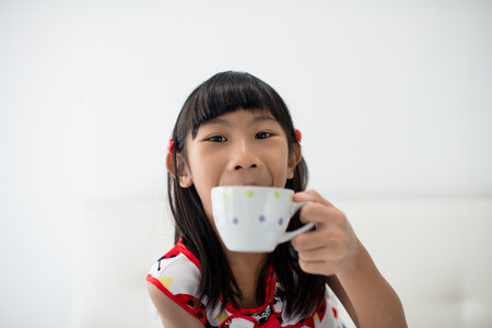 Asian girl holding a cup of milk at home.の写真素材