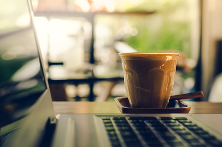 Coffee cup and laptop for business, Selective focus on coffeeの写真素材