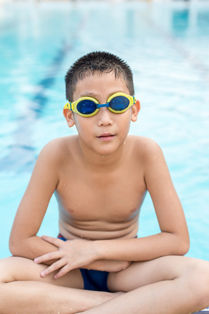 Activities on the pool, child sitting at swimming pool in  summertimeの写真素材