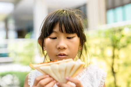 Asian girl eating bread in the garden at home. DOFの写真素材